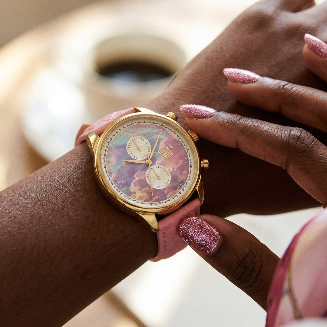 Pink unicorn watch with a gold case, iridescent dial, and pink leather strap worn on a wrist with glittery nails.